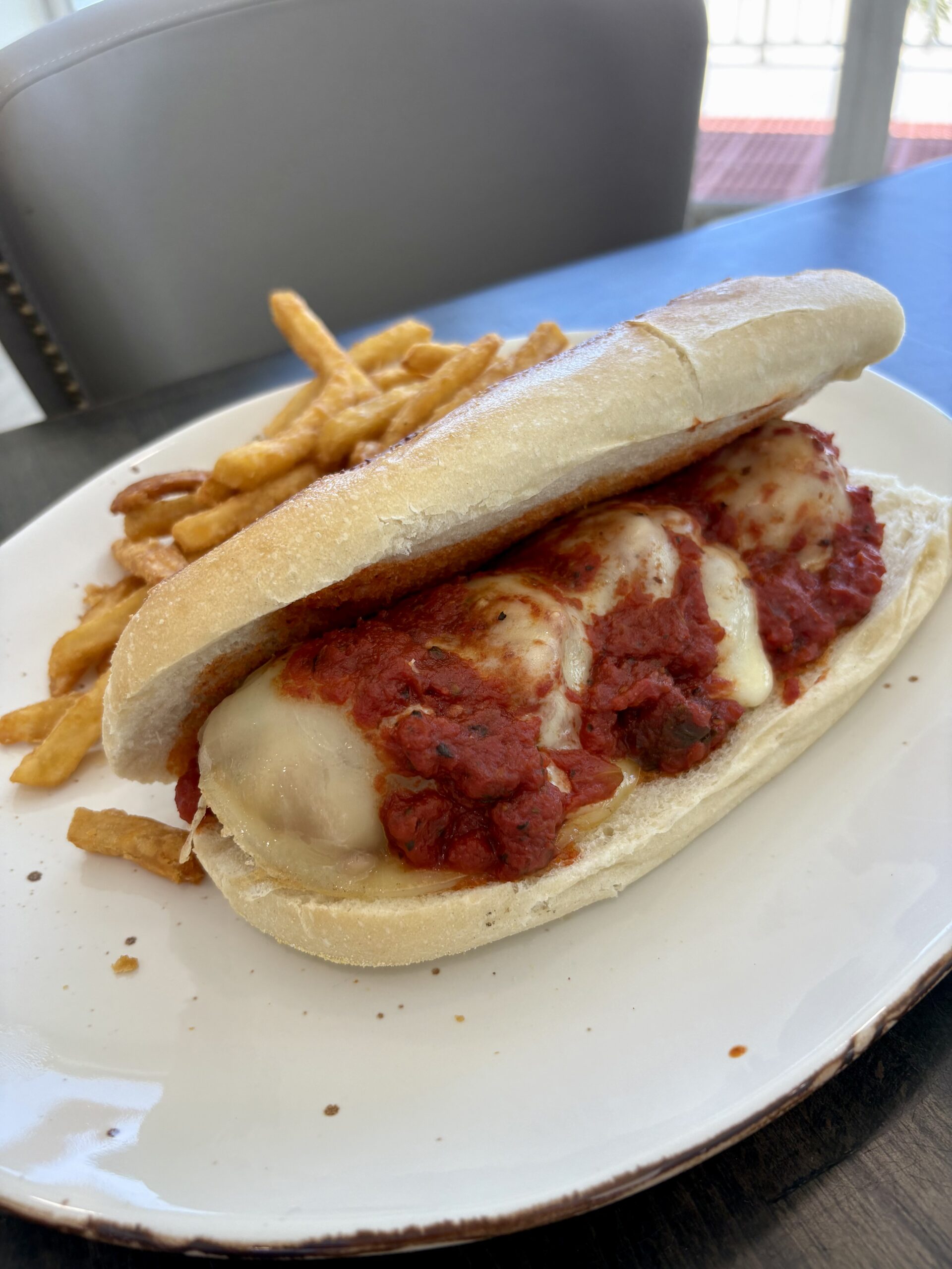 Plate of meatball sub with sides served on a white dish.