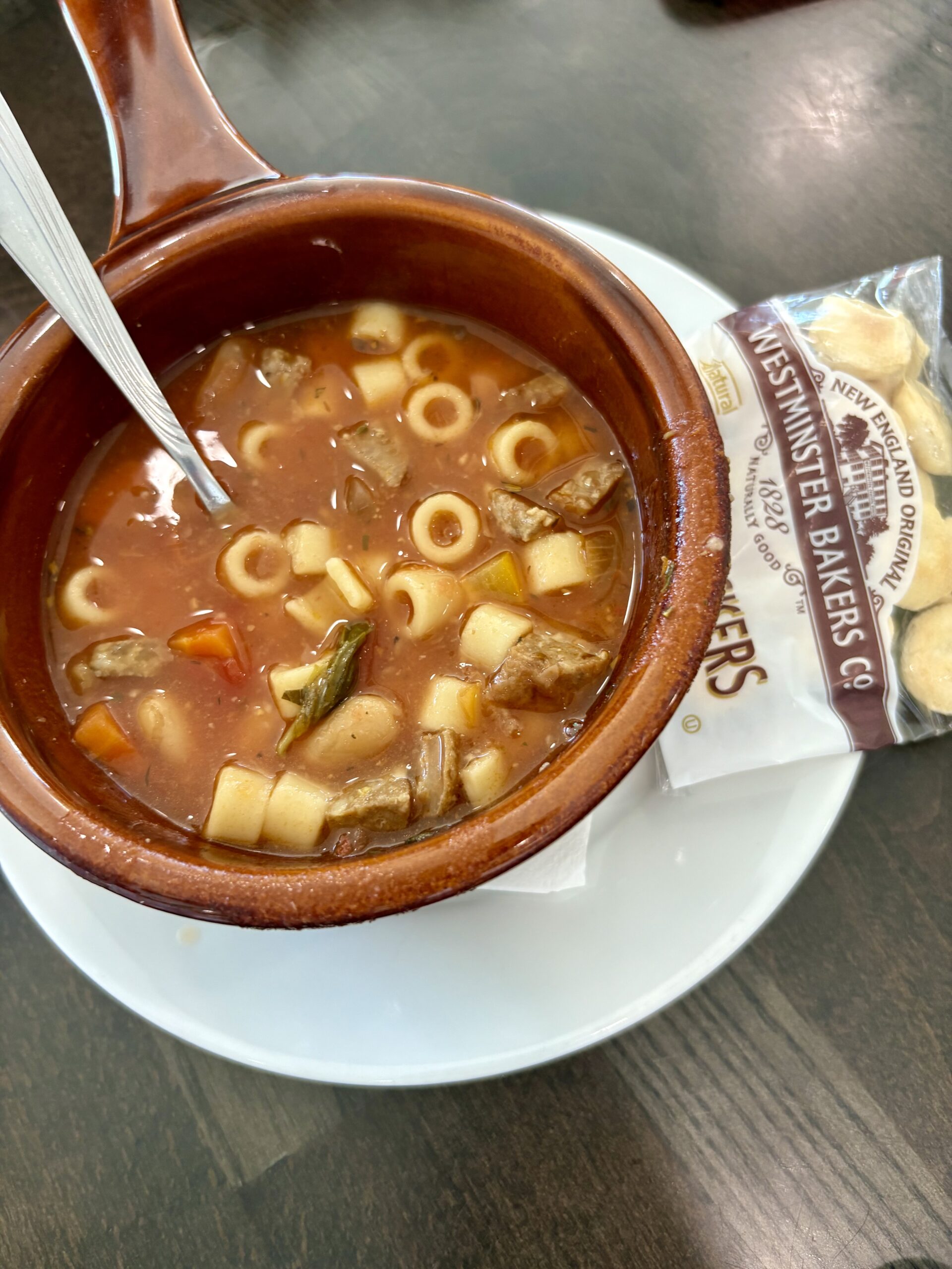 Cup of soup from the restaurant, sitting on a dining table.
